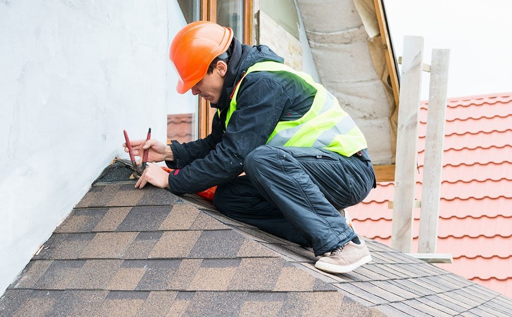 Roofer repairing an asphalt shingle roof